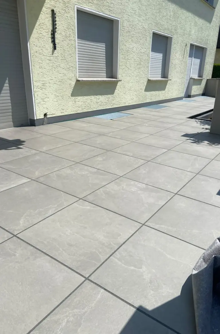 Fertig verlegte Terrasse aus großen grauen Platten vor einem Haus